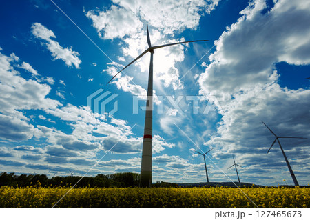 A field of wind turbines generating energy standing in a green field. A field of wind turbines generating energy standing in a green field. 127465673