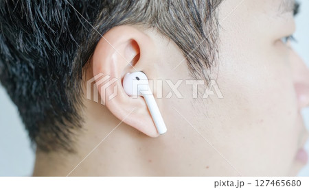 《AI画像》Bluetoothイヤホンを付けた若い男性のクローズアップ 127465680