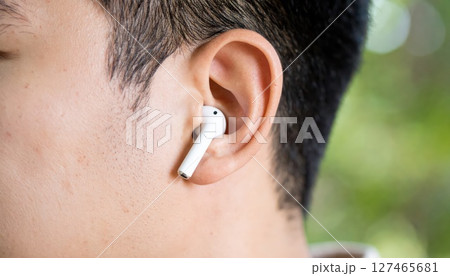 《AI画像》Bluetoothイヤホンを付けた若い男性のクローズアップ 127465681