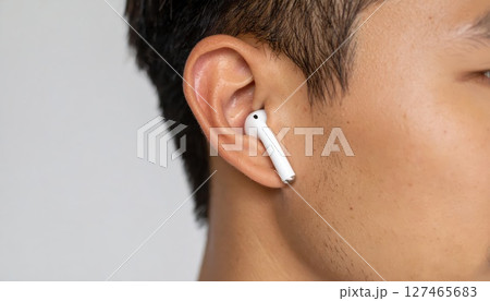 《AI画像》Bluetoothイヤホンを付けた若い男性のクローズアップ 127465683