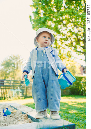 Toddler playing with a shovel in the sandbox on the playground. Boy playing in nature. 2 year old boy enjoying green grass in the park on a sunny summer day. Toddler playing with a shovel in the sandbox on the playground. Boy playing in nature. 2 year old boy enjoying green grass in the park on a sunny summer day. 127465722