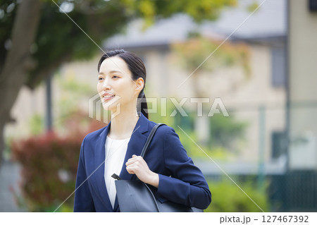 住宅街を歩くスーツを着た若い女性 住宅街を歩くスーツを着た若い女性 127467392