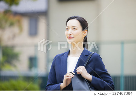 住宅街を歩くスーツを着た若い女性 127467394
