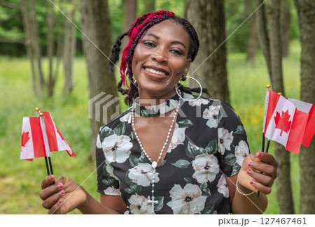 Happy African American Woman Celebrating Canada Day July 1st with Red Maple Leaf Flags 127467461
