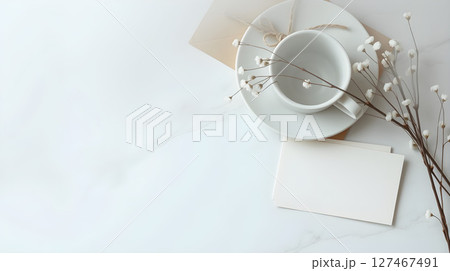 Elegant minimal composition with a white teacup, saucer, and card on a marble surface. 127467491