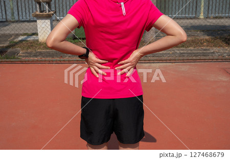 Cropped shot view of female runner suffering from backache or sore waist. Cropped shot view of female runner suffering from backache or sore waist. 127468679