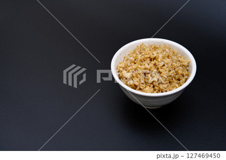 黒背景の茶碗によそう玄米ご飯 127469450