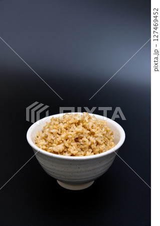 黒背景の茶碗によそう玄米ご飯 127469452