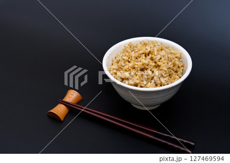 黒背景の茶碗によそう玄米ご飯 127469594
