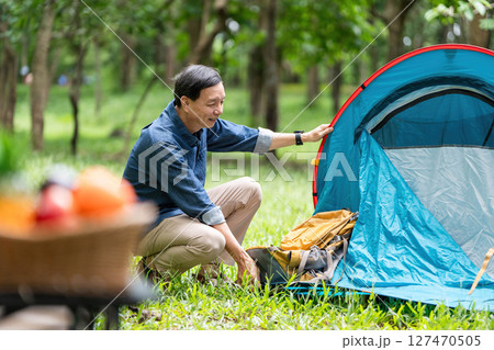 Family adventure. A father setting up a tent while enjoying nature. Family adventure. A father setting up a tent while enjoying nature. 127470505