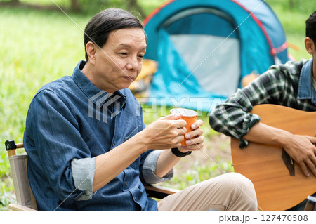 Family moments captured. Father enjoying coffee while son plays guitar. 127470508