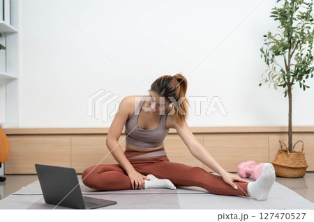 Yoga practice at home. Young woman performing forward bends for flexibility and relaxation. Yoga practice at home. Young woman performing forward bends for flexibility and relaxation. 127470527