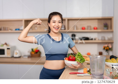ESG and Empowerment. Confident woman flexing her muscles while holding fresh produce. 127470629