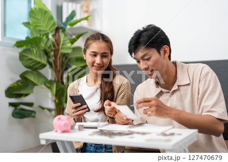 Digital Financial Management. Couple reviewing budget with smartphone and notebook. 127470679