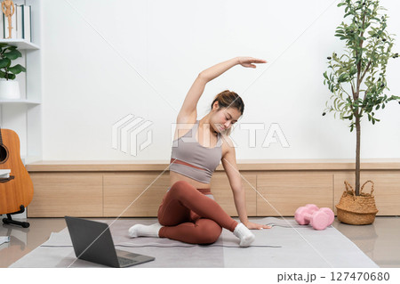 Yoga practice at home. Young woman performing side stretches for flexibility and mindfulness. Yoga practice at home. Young woman performing side stretches for flexibility and mindfulness. 127470680