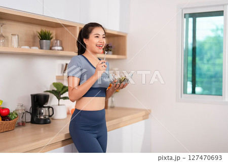 ESG and Enjoying Healthy Food. Woman savoring a fresh salad in her kitchen. ESG and Enjoying Healthy Food. Woman savoring a fresh salad in her kitchen. 127470693