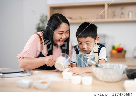 Family Baking Experience. A mother and son preparing treats together, sharing smiles in the kitchen. Family Baking Experience. A mother and son preparing treats together, sharing smiles in the kitchen. 127470694