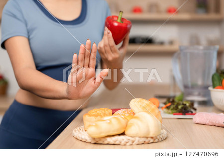 ESG and Healthy Choices. Woman rejecting unhealthy snacks in a modern kitchen. 127470696