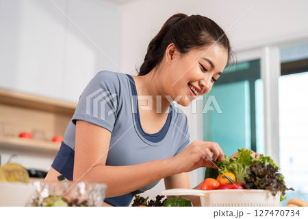ESG and Healthy Meal Prep. Woman smiling while handling fresh vegetables in her kitchen. ESG and Healthy Meal Prep. Woman smiling while handling fresh vegetables in her kitchen. 127470734
