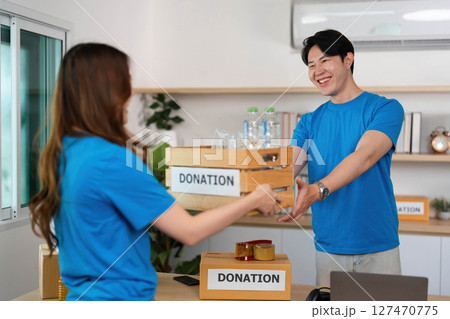 Donation Activity. Volunteers engaging in charitable giving with donation boxes. 127470775