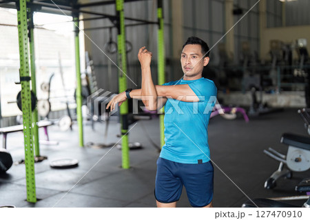 Fitness Stretching: Man Preparing for Workout in Gym 127470910