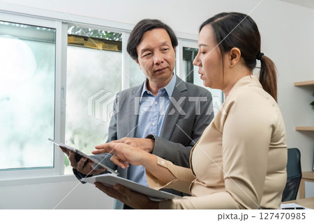 Business Presentation. Professionals discussing insights on digital devices in office. 127470985