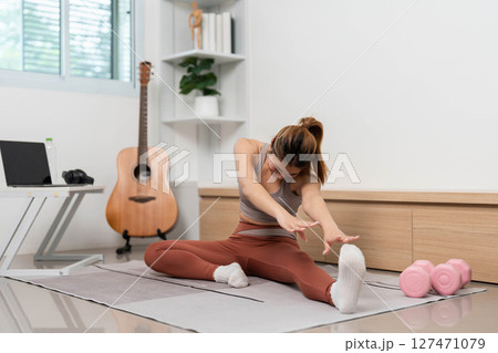 Yoga and flexibility. Woman stretching forward on mat during home workout. 127471079