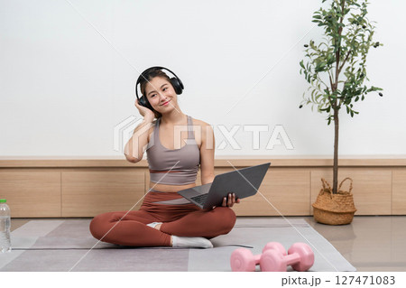 Yoga and Technology Integration. Woman listening to music while practicing yoga at home. Yoga and Technology Integration. Woman listening to music while practicing yoga at home. 127471083
