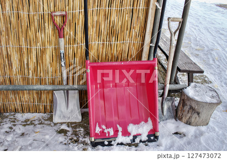 建物の片隅に雪かき用の道具が置かれている風景 127473072