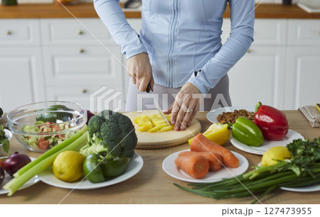 Woman cutting salad healthy vegans cooking at home in modern kitchen, vegetarian diet assortiment 127473955