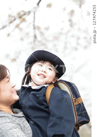 桜と入園式を迎えた3歳の女の子と母親 127474255