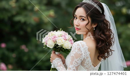 ガーデンウェディングでブーケを持ち、後ろに振り向く白いウェディングドレスを着た花嫁の姿 ガーデンウェディングでブーケを持ち、後ろに振り向く白いウェディングドレスを着た花嫁の姿 127474401
