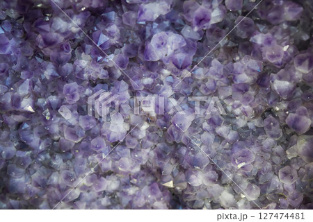 Close-up of natural amethyst crystals with shimmering purple hues, creating a textured abstract background perfect for use as copy space in design. 127474481