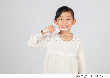 Happy girl with a toothbrush smiles, revealing a tooth gap. The dentist explains tooth loss and proper care, making oral hygiene a fun and essential routine for kids. isolated white background 127474704