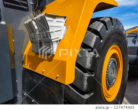 Heavy machinery tire and fender details capture in bright sunlight at construction site during daytime activity Heavy machinery tire and fender details capture in bright sunlight at construction site during daytime activity 127474985