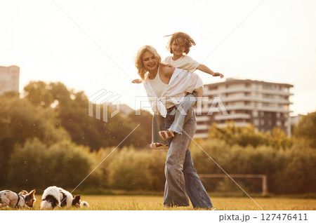Beautiful mother with her little daughter and dogs are on the summer field together 127476411