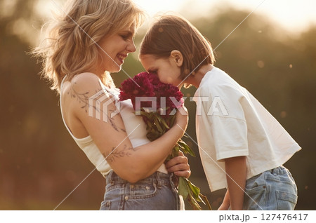 Mother with her little daughter is on the field with red flowers 127476417