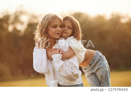 Conception of love, embracing each other. Woman with her little daughter are on the summer field together Conception of love, embracing each other. Woman with her little daughter are on the summer field together 127476420