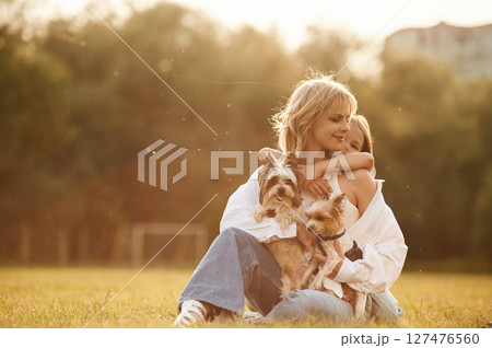 Embracing the mother. Beautiful mother with her little daughter and dogs are on the summer field together Embracing the mother. Beautiful mother with her little daughter and dogs are on the summer field together 127476560