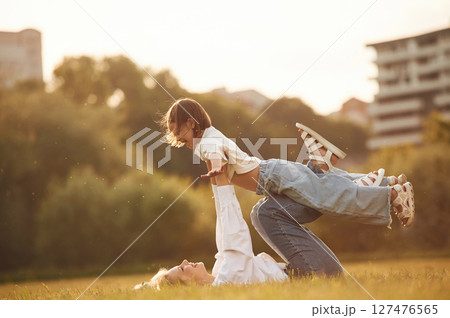 Kid in the hands of woman. Mother with her little daughter are on the summer field together Kid in the hands of woman. Mother with her little daughter are on the summer field together 127476565