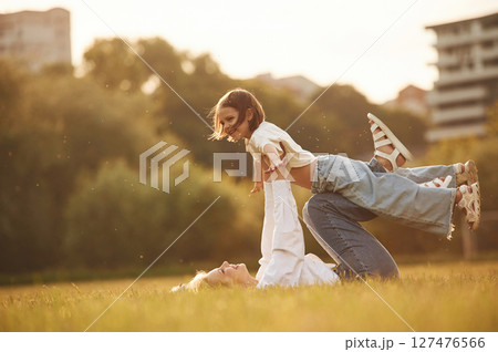 Kid in the hands of woman. Mother with her little daughter are on the summer field together Kid in the hands of woman. Mother with her little daughter are on the summer field together 127476566