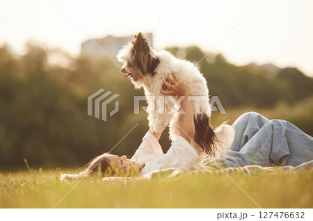 Little girl is playing with dog on the summer field Little girl is playing with dog on the summer field 127476632