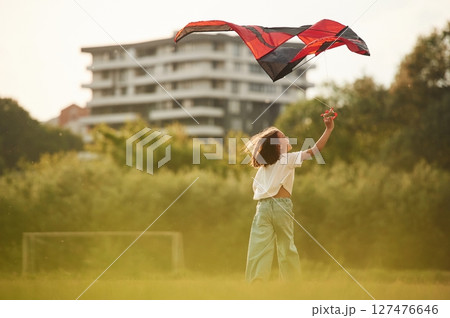 View from behind. Little girl is playing with kite on the field 127476646
