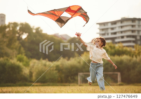 Little girl is playing with kite on the field Little girl is playing with kite on the field 127476649