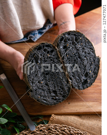 Baker Hand Presenting Homemade fresh baked black charcoal sourdough bread. Showing crumb inside. Baker Hand Presenting Homemade fresh baked black charcoal sourdough bread. Showing crumb inside. 127477071