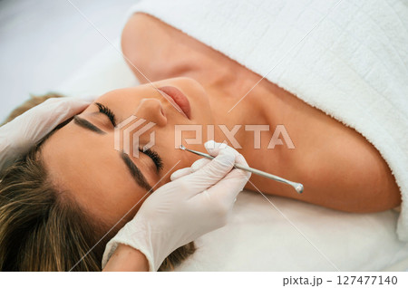 Using cosmetic spoon. Woman face getting facial care by beautician hands at spa salon Using cosmetic spoon. Woman face getting facial care by beautician hands at spa salon 127477140