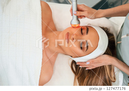 Apparatus for galvanization is used. Woman face getting facial care by beautician hands at spa salon Apparatus for galvanization is used. Woman face getting facial care by beautician hands at spa salon 127477176