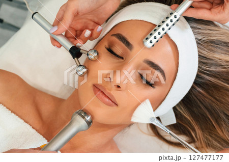 Many of different cosmetitian tools. Woman face getting facial care by beautician hands at spa salon Many of different cosmetitian tools. Woman face getting facial care by beautician hands at spa salon 127477177