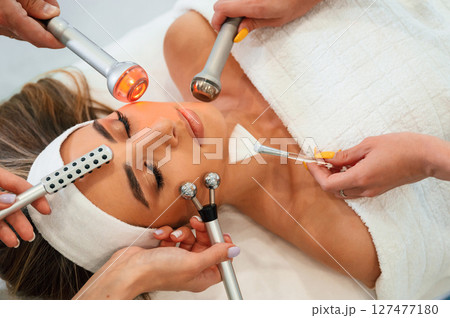 Many of different cosmetitian tools. Woman face getting facial care by beautician hands at spa salon Many of different cosmetitian tools. Woman face getting facial care by beautician hands at spa salon 127477180