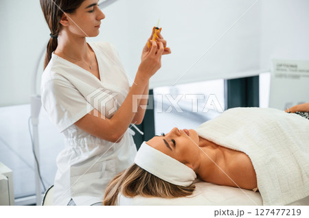 Getting ready for injection. Woman face getting facial care by beautician hands at spa salon 127477219